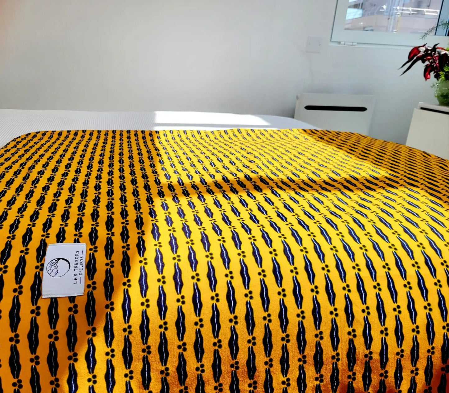 Couverture JASIRI illuminée par la lumière du soleil – création artisanale en tissu wax africain et minky moelleux. Produit fait main Les Trésors d’Elikya, parfait pour offrir chaleur et confort à bébé.