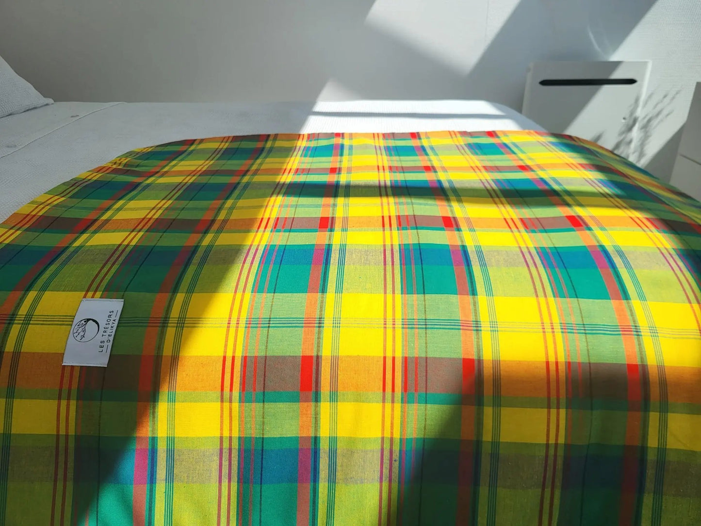 Couverture MADELYOS illuminée par la lumière du soleil – création artisanale en tissu madras antillais et minky moelleux. Produit fait main Les Trésors d’Elikya, parfait pour offrir chaleur et confort à bébé.