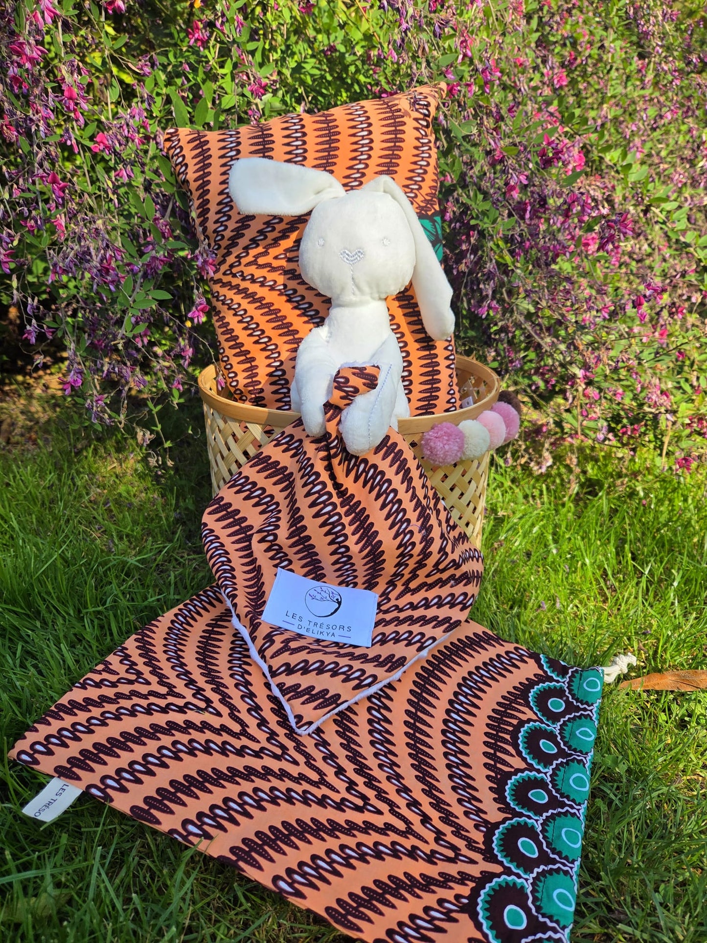 Coffret cadeau d’éveil KINABÉ en tissu Wax beige saumon, avec doudou, coussin et panier en bambou – création artisanale Les Trésors d’Elikya.
