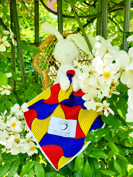 Doudou lapin Bunny Wax AMORIA avec mini-couverture en tissu Wax rouge, bleu et jaune – création artisanale Les Trésors d’Elikya