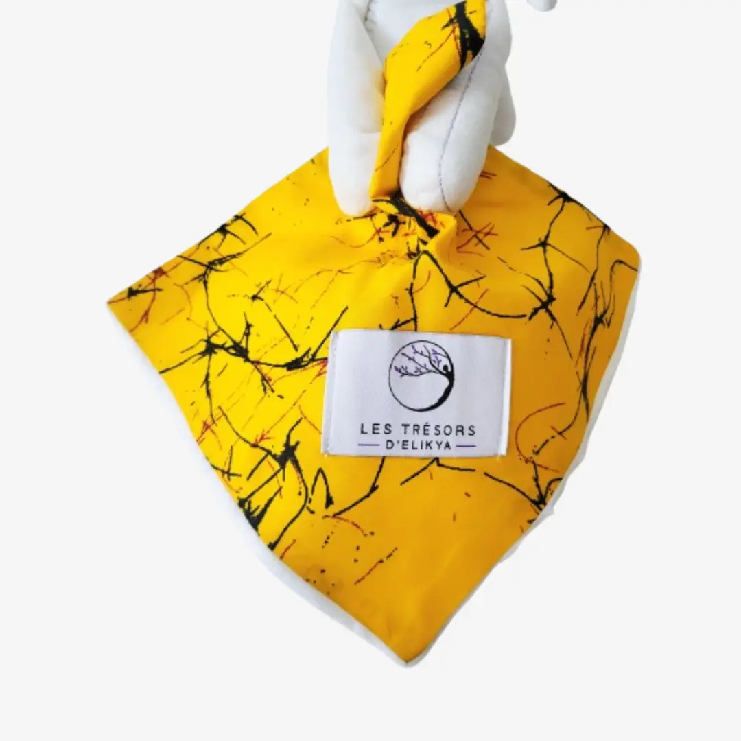 Zoom sur la couverture et l’étiquette du Bunny Wax MAYELI– doudou lapin bébé en tissu wax africain, création artisanale Les Trésors d’Elikya. Fait main avec soin, ce doudou éthique est un cadeau de naissance unique et durable.