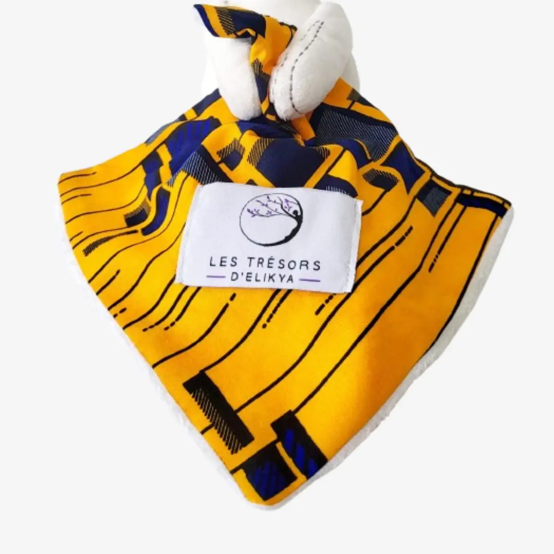 Zoom sur la couverture et l’étiquette du Bunny Wax TANZURA – doudou lapin bébé en tissu wax africain, création artisanale Les Trésors d’Elikya. Fait main avec soin, ce doudou éthique est un cadeau de naissance unique et durable.