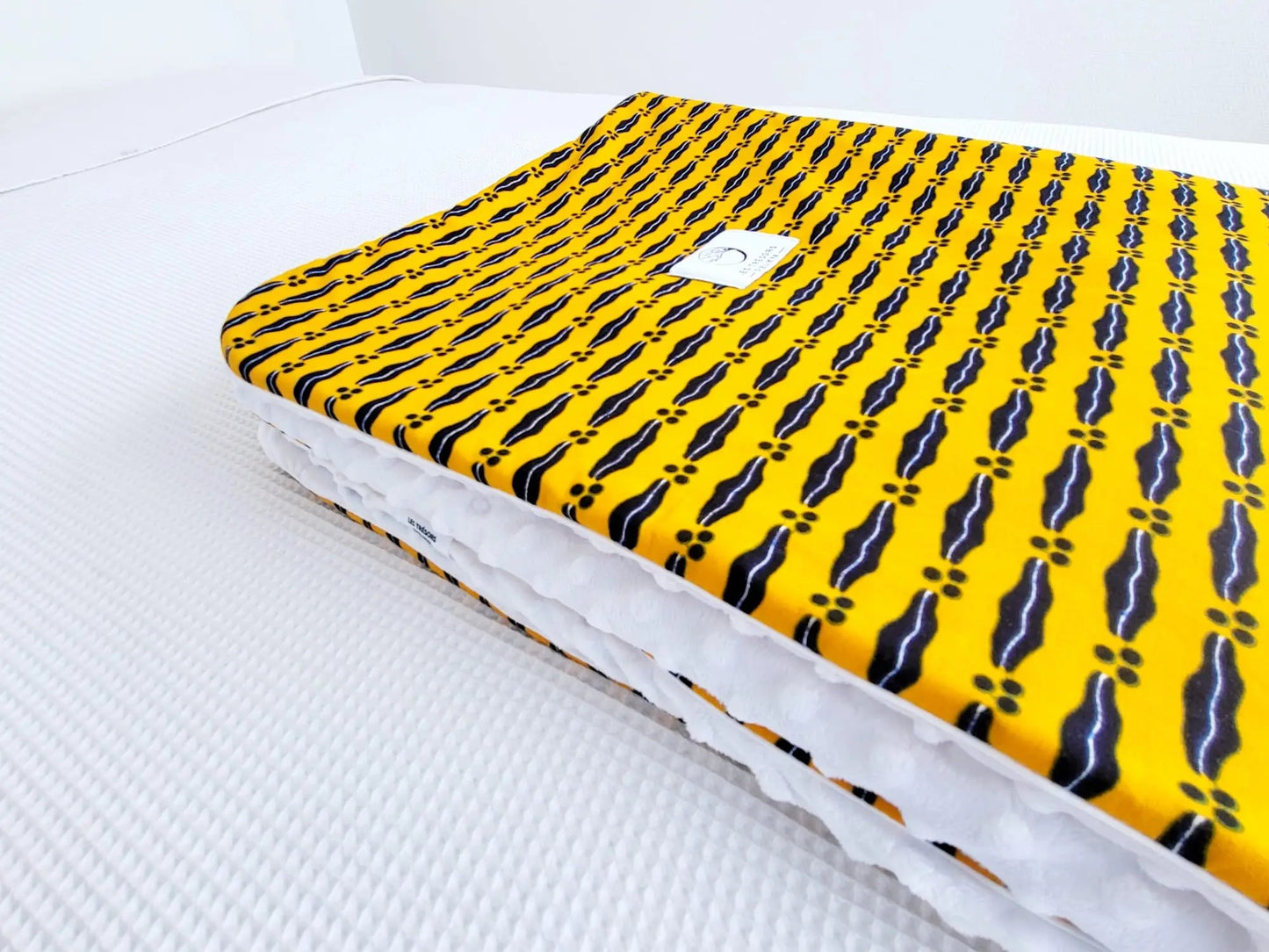 Zoom sur le carré de la couverture JASIRI – tissu wax africain Mon mari est capable doublure minky ultra douce et finitions passepoils élégantes. Création artisanale Les Trésors d’Elikya pour envelopper bébé de douceur.