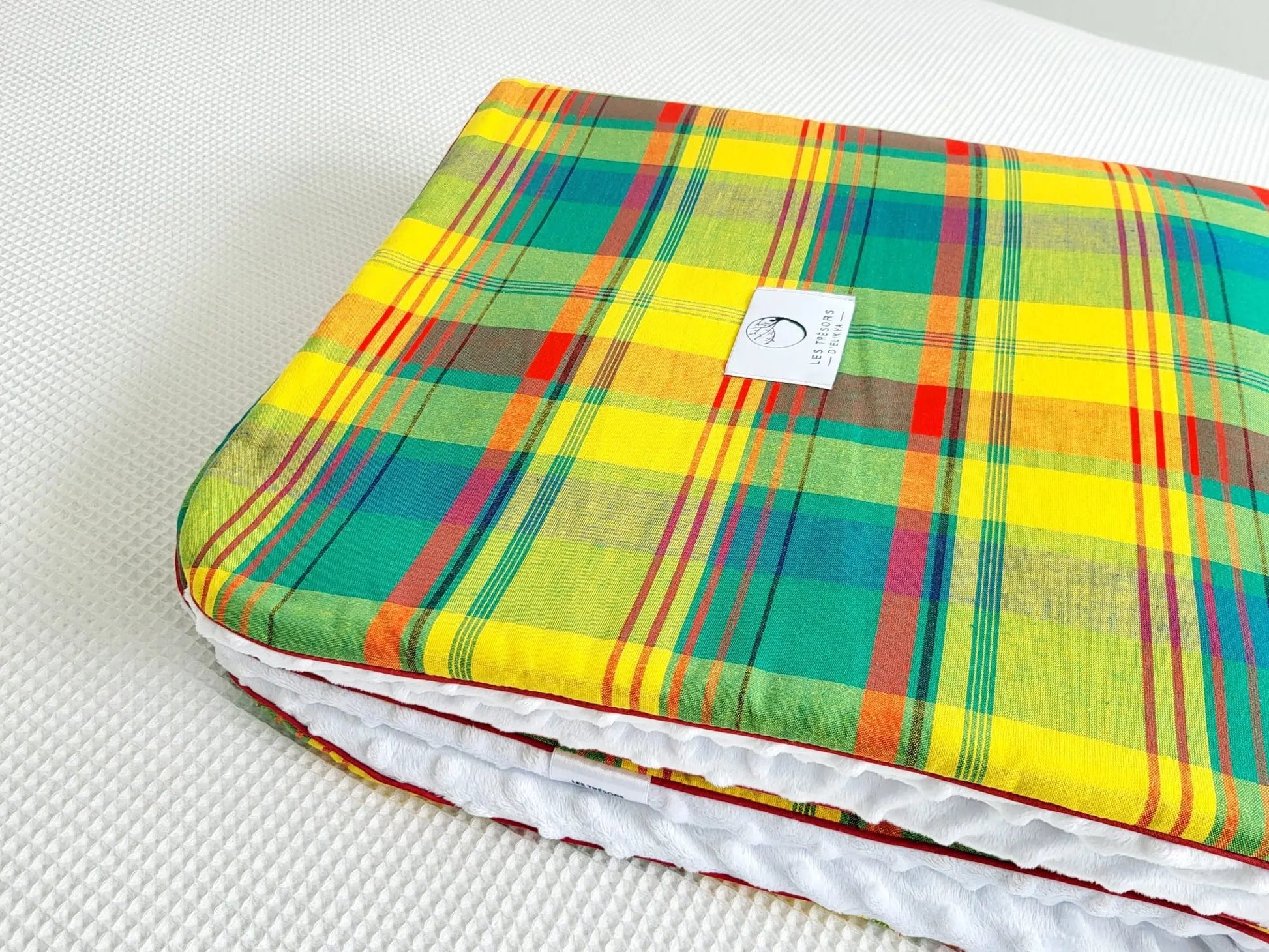 Zoom sur le carré de la couverture MADELYOS – tissu madras antillais vert, rehaussé de lignes jaunes et rouges, doublure minky ultra douce et finitions passepoils élégantes. Création artisanale Les Trésors d’Elikya pour envelopper bébé de douceur.