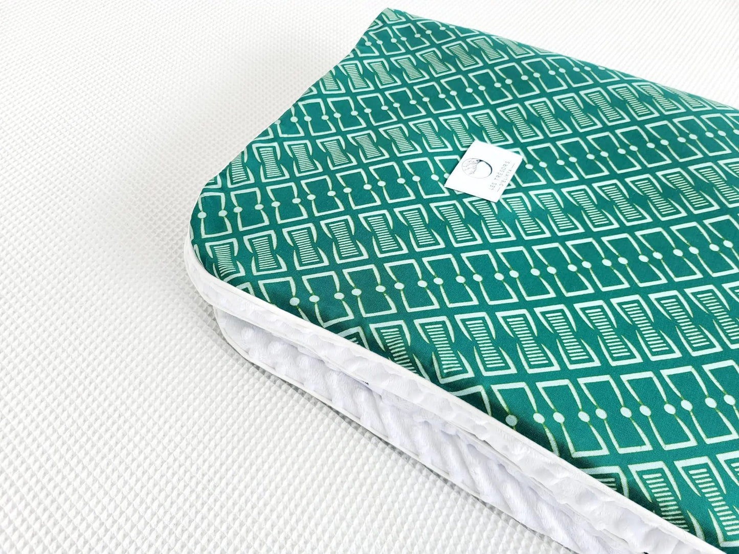 Zoom sur le carré de la couverture NAIORIA – tissu wax africain avec un motif graphique vert profond orné de formes géométriques ivoire et de pois réguliers,
doublure minky ultra douce et finitions passepoils élégantes. Création artisanale Les Trésors d’Elikya pour envelopper bébé de douceur.