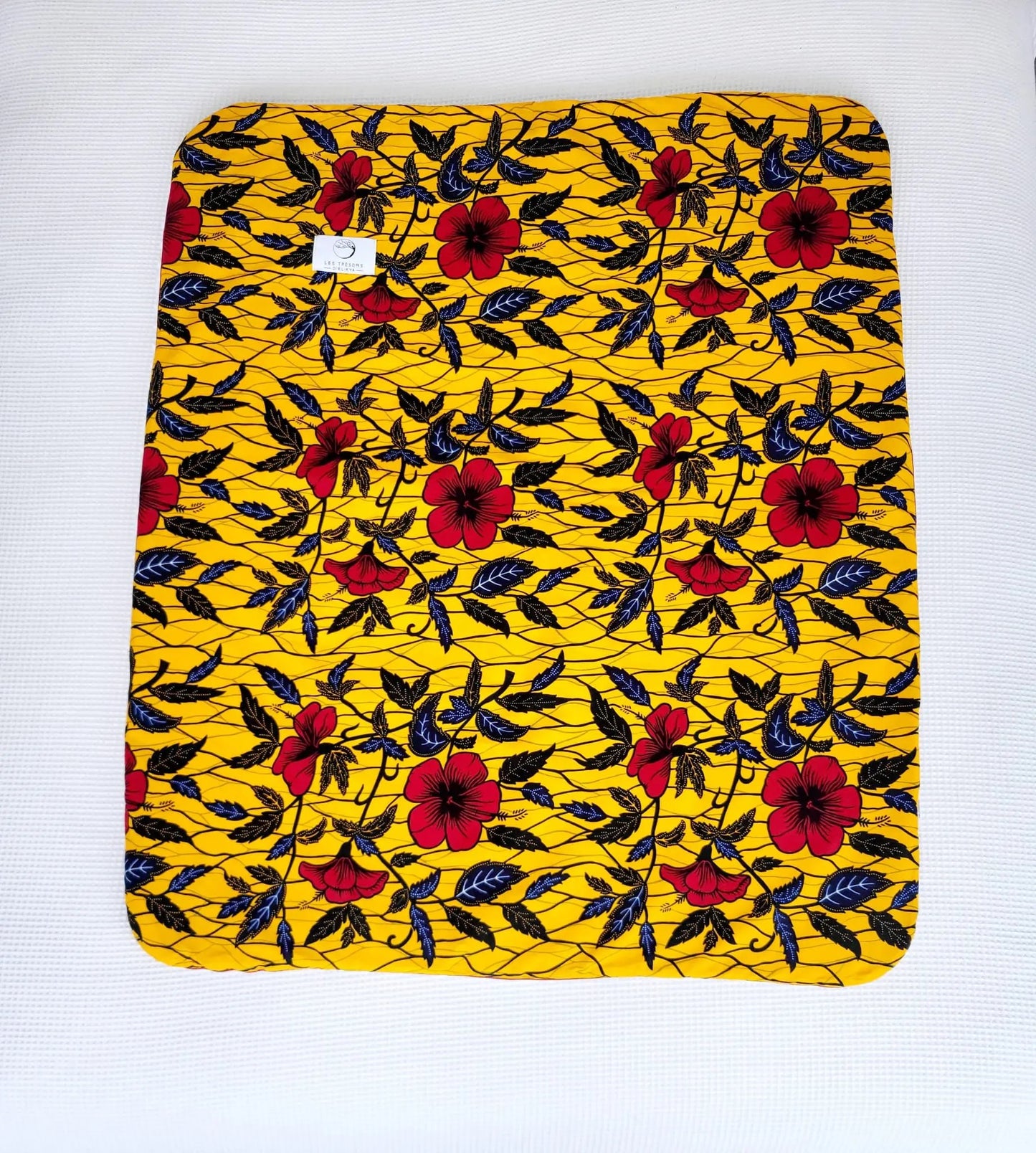 Vue complète de la couverture AYANA– face en tissu wax africain aux tons rouge, noir et jaune, confection artisanale Les Trésors d’Elikya. Couverture bébé douce, moelleuse et raffinée, idéale comme cadeau de naissance.