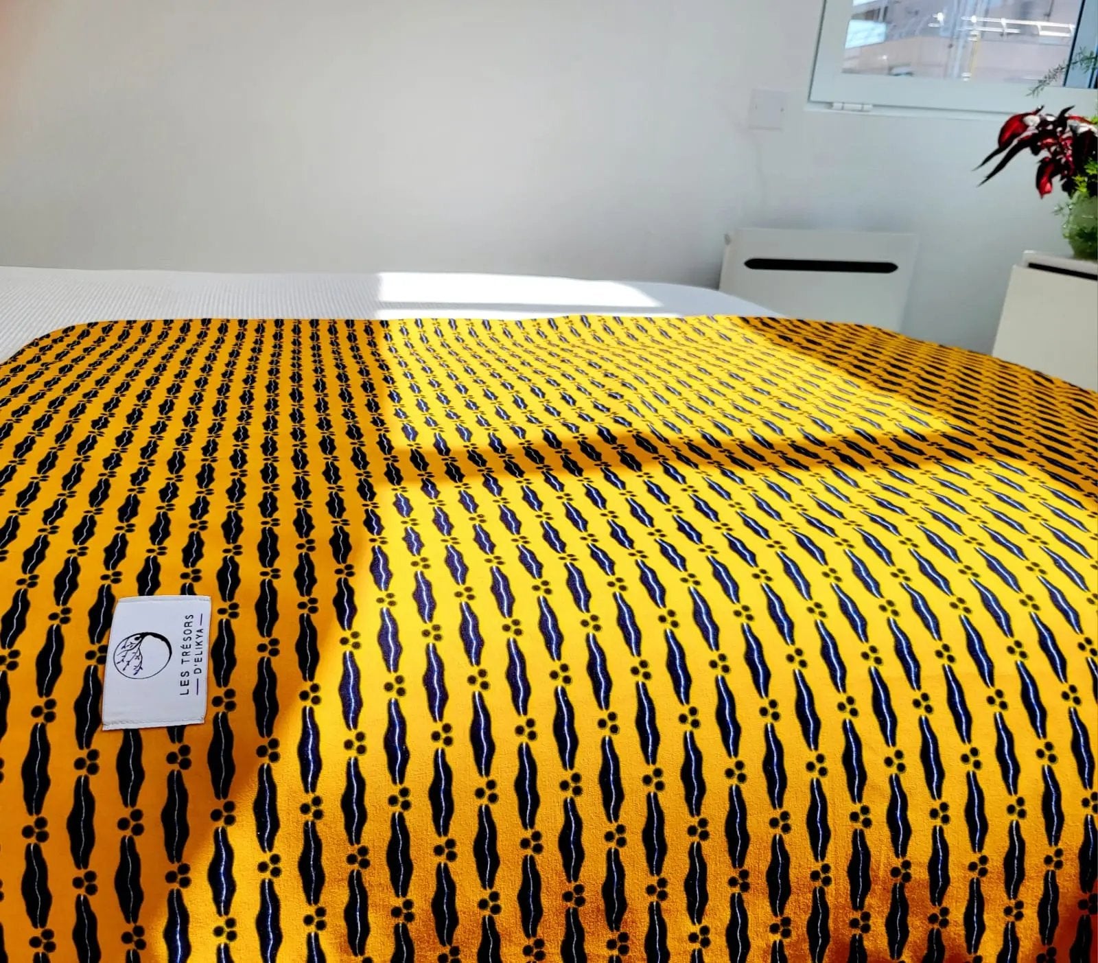 Couverture JASIRI illuminée par la lumière du soleil – création artisanale en tissu wax africain et minky moelleux. Produit fait main Les Trésors d’Elikya, parfait pour offrir chaleur et confort à bébé.