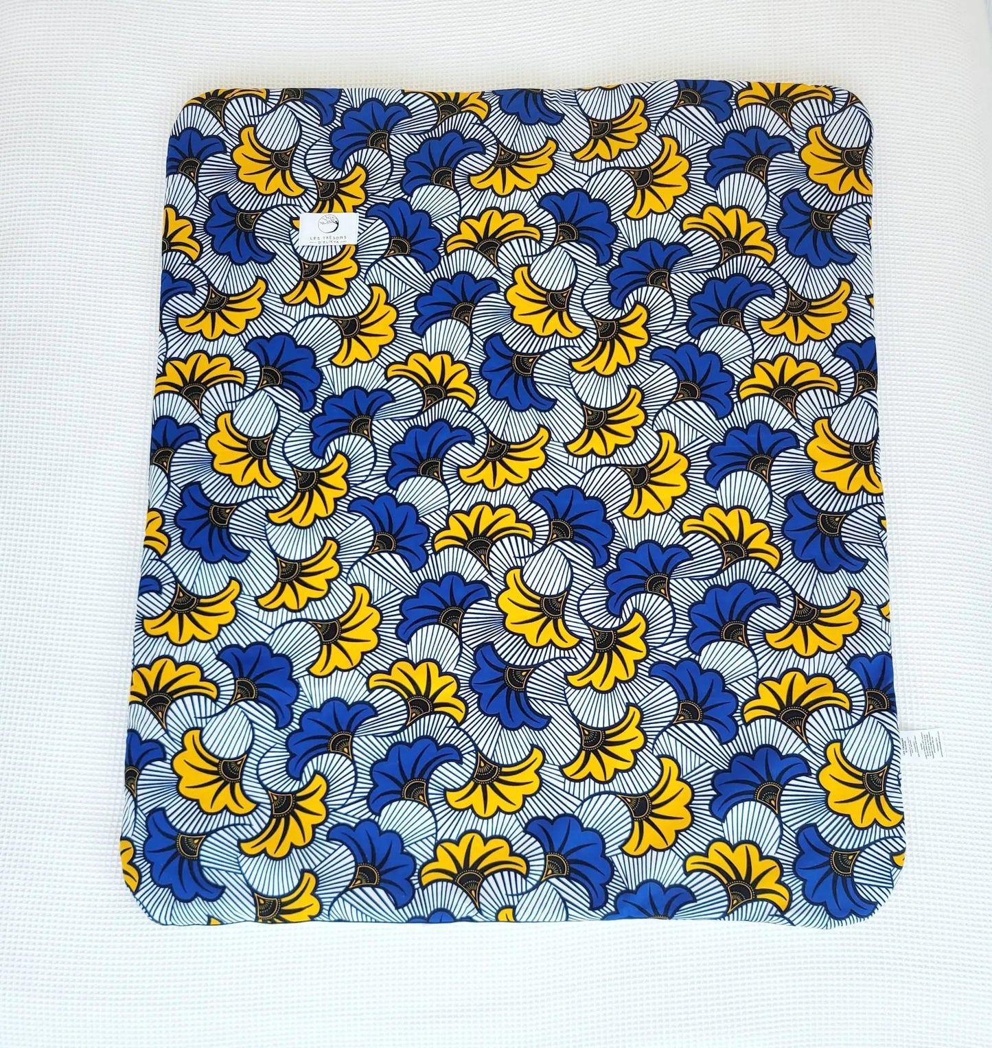Vue complète de la couverture MIRELYS– face en tissu wax africain fleurs de mariage jaunes et bleues sur fond blanc, confection artisanale Les Trésors d’Elikya. Couverture bébé douce, moelleuse et raffinée, idéale comme cadeau de naissance.