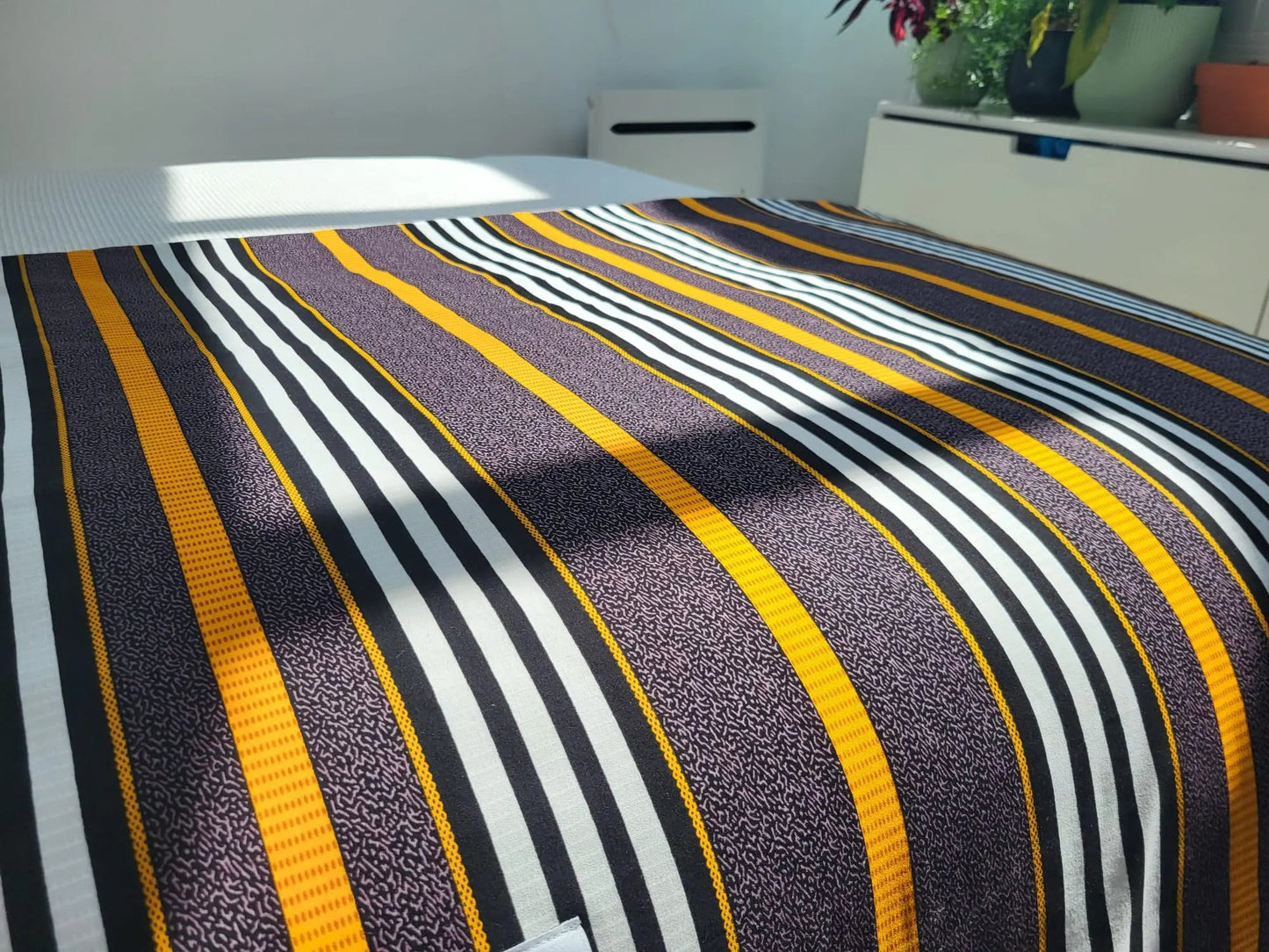 Couverture TIKA illuminée par la lumière du soleil – création artisanale en tissu wax africain et minky moelleux. Produit fait main Les Trésors d’Elikya, parfait pour offrir chaleur et confort à bébé.