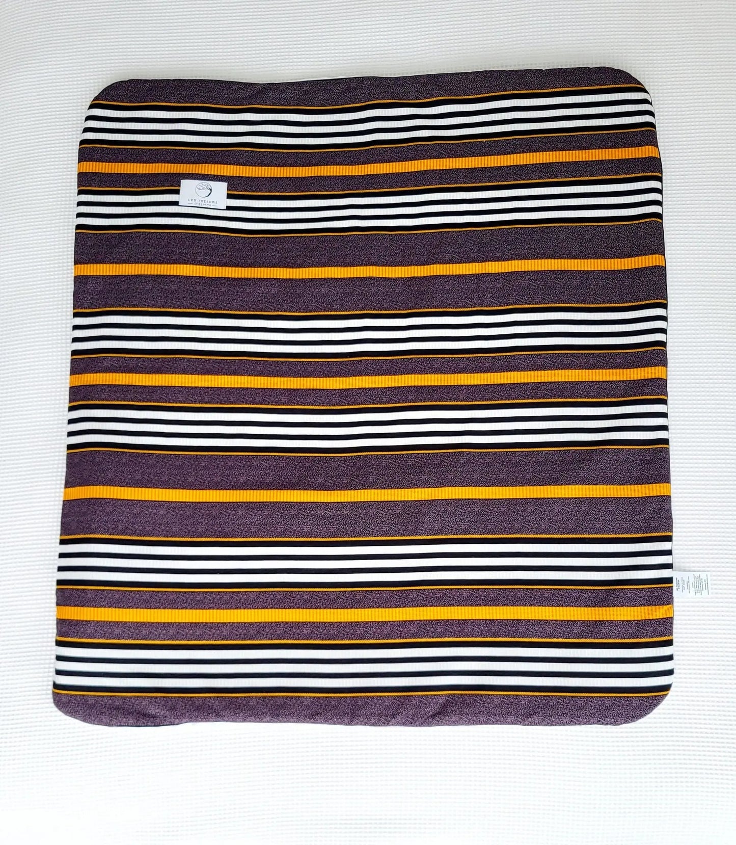 Vue complète de la couverture TIKA – face en tissu wax africain aux lignes raffinées mêlant des tons ocre, noir et blanc, dans une composition à la fois élégante et structurée. Les Trésors d’Elikya. Couverture bébé douce, moelleuse et raffinée, idéale comme cadeau de naissance.