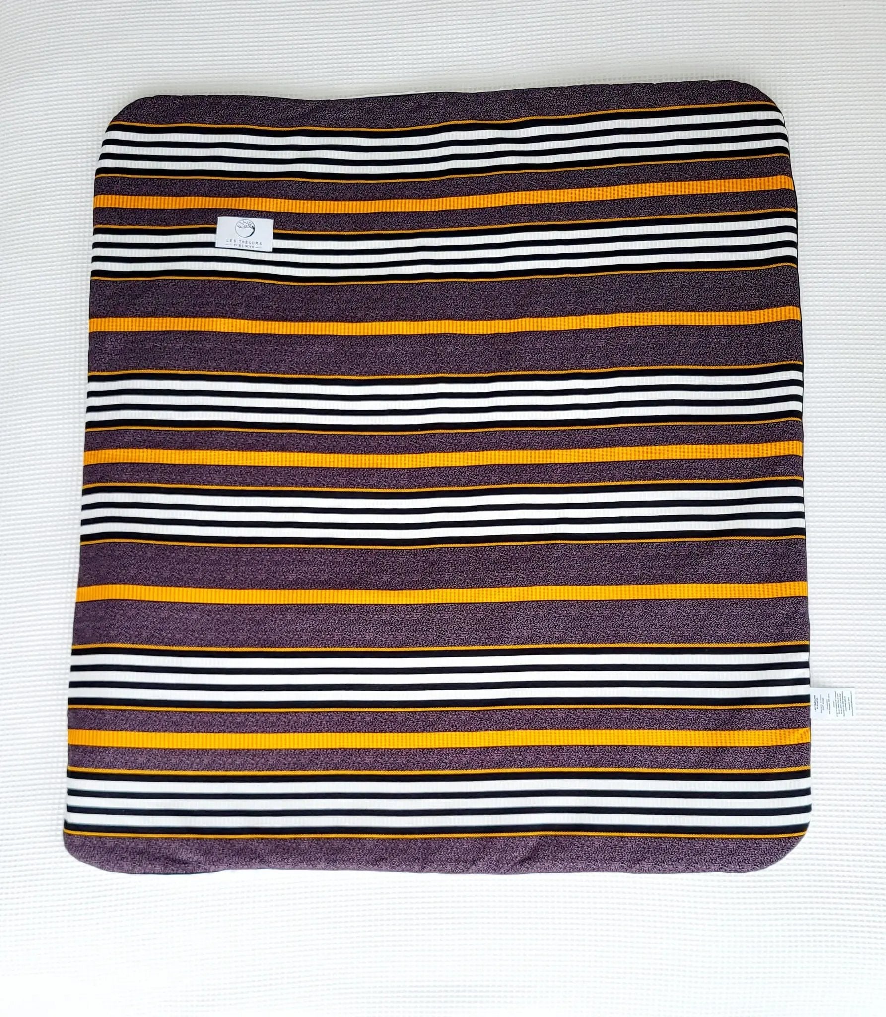 Vue complète de la couverture TIKA – face en tissu wax africain aux lignes raffinées mêlant des tons ocre, noir et blanc, dans une composition à la fois élégante et structurée. Les Trésors d’Elikya. Couverture bébé douce, moelleuse et raffinée, idéale comme cadeau de naissance.
