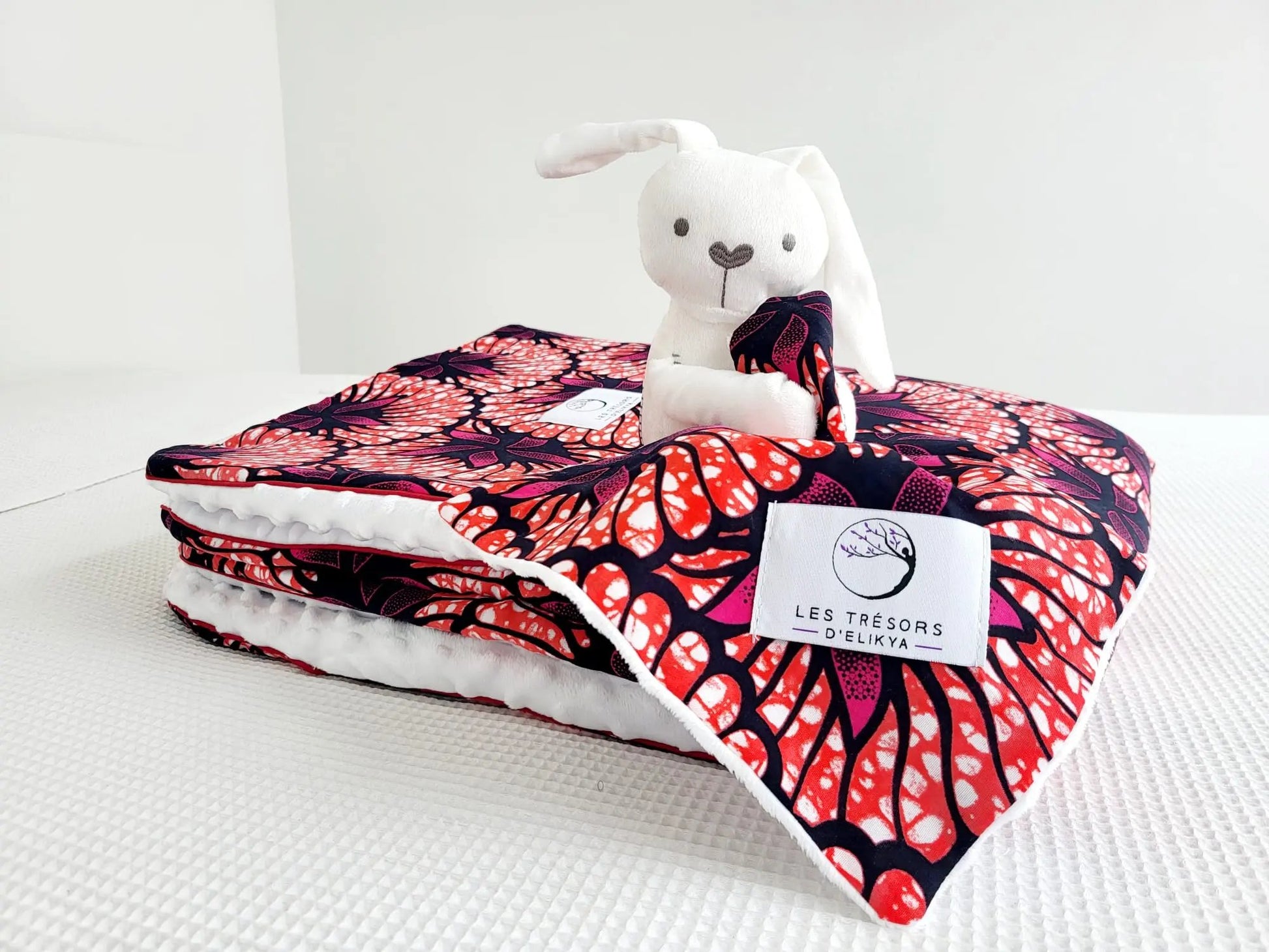 Zoom sur la mini couverture du doudou Bunny Wax ROSÉLIA et l’étiquette Les Trésors d’Elikya – peluche bébé faite main en tissu wax africain aux motifs floraux. Détail de confection artisanale et idée de cadeau de naissance unique.