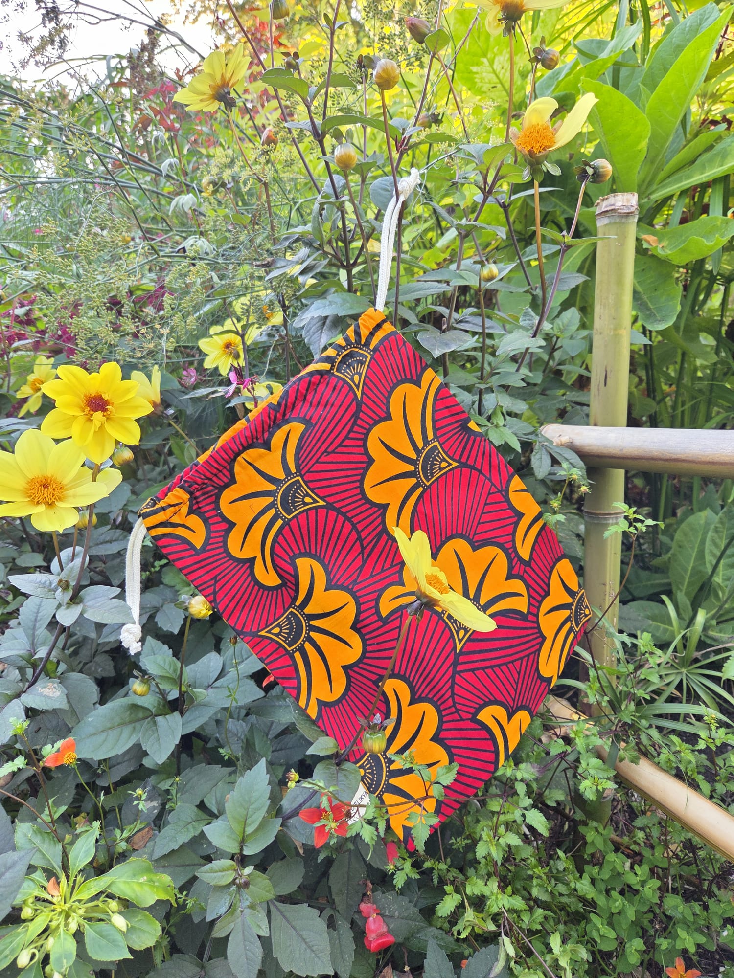 Pochette surprise du coffret cadeau SOLÉLYS en tissu Wax jaune et rouge, réutilisable.